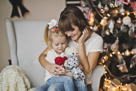 Mother and daughter in the white chair in front of a huge clock.の写真素材
