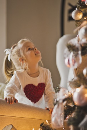 Baby playing with decorations on a Christmas tree.の写真素材