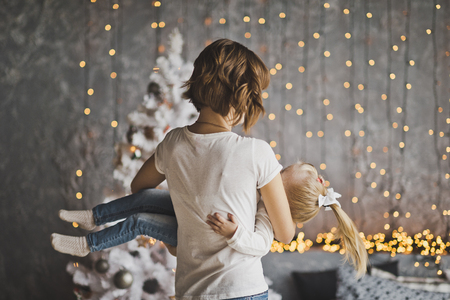 Happy mother holding her daughter in her arms on the background of Christmas decorations.の写真素材