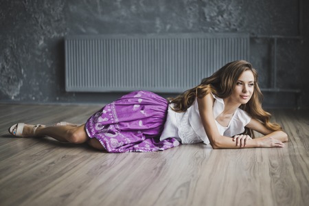 A girl with long brown hair posing on the parquet floor.の写真素材