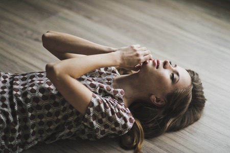 The girl lay on the parquet floor, arms outstretched.の写真素材