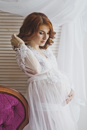 Redhead pregnant girl in a delicate situation.の写真素材