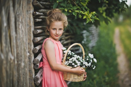 The child standing at the fence with a basket of flowers.の写真素材