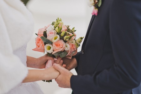 Palms of newlyweds with a bouquet of flowers in them.の写真素材