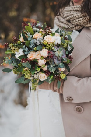 Original bouquet of flowers in the hands of women against the winter landscape.の写真素材