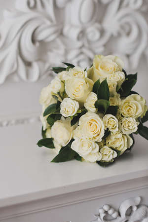 A neat bouquet of beige roses lying on a white table.の写真素材
