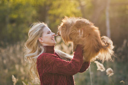 Happy mistress playing in nature with her dwarf Spitz.