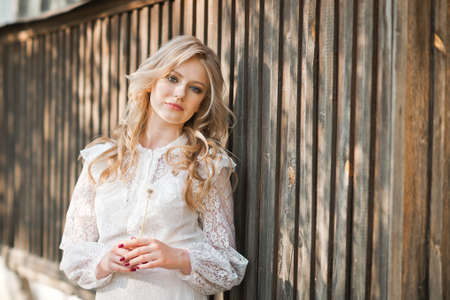Young girl stands leaning against the fenceの写真素材