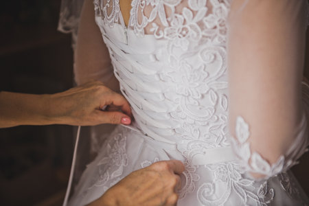 Mom helps her daughter dress up in a snow-white dress for the wedding.の写真素材