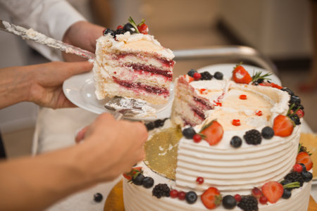 The process of cutting a delicious birthday cake decorated with flowers from edible materials.