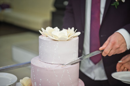 The process of cutting the wedding cake at the celebration.