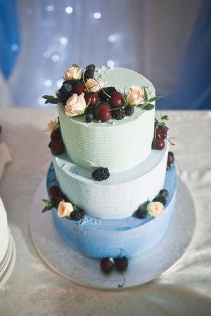 Wedding cake in three tiers, decorated with fresh flowers and berries.の写真素材