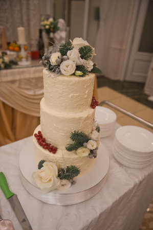 White wedding cake decorated with live roses, berries and twigs.の写真素材