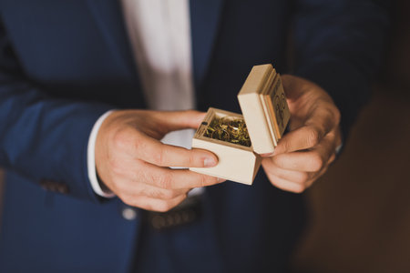 The groom is holding a beautiful wooden box with gold wedding rings.