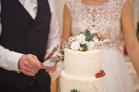 Wedding white cake, decorated with fresh flowers and twigs, stands on the background of the bride...