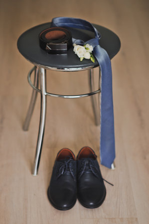 The grooms belt, boutonniere and tie lie on a stool.の写真素材