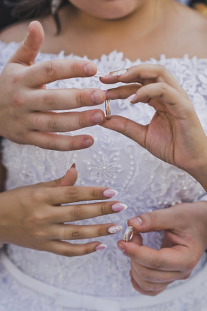 The husband gently embraces the hands of the bride with wedding rings.