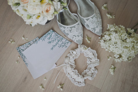 Wedding shoes, brides garter, wedding invitations, delicate bouquet of roses.の写真素材