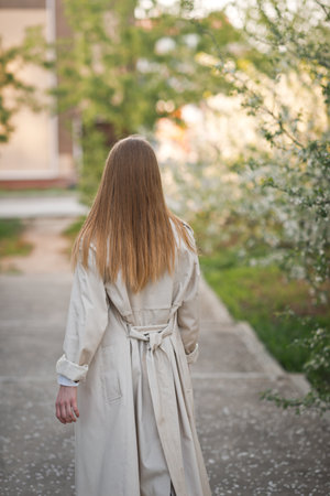 A girl in a raincoat stands with her back to the viewer.の写真素材