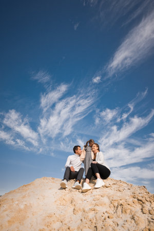 A young family with a daughter among the sand and blue sky.の写真素材