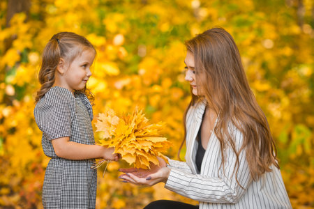 Photo of mom with daughter and yellow leaves.の写真素材
