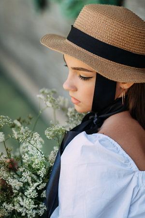A large young female portrait in a hat and with black ribbons.
