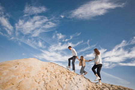A family poses standing on a mountain of sand against the sky.の写真素材