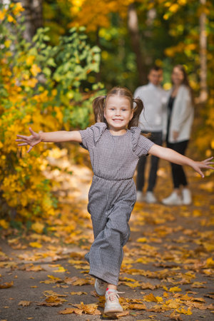Dad, mom and daughter are walking in the autumn forest.の写真素材