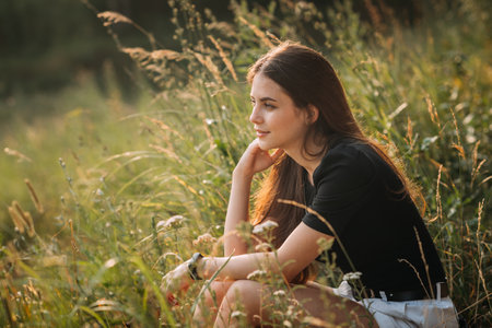 The beauty sits in the summer among the grass in the meadow.の写真素材
