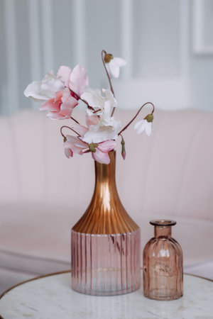 Unusual vases on the table with pink flowers.の写真素材