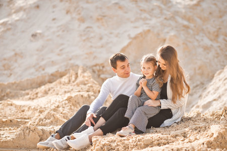 A young family is sitting among the sandy mountains.の写真素材