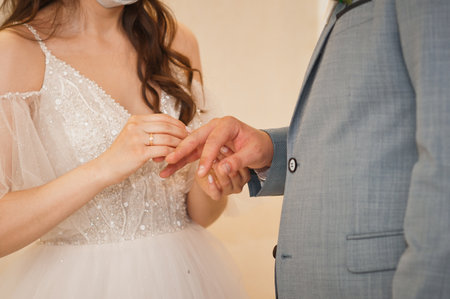 Gentle embrace of the hands of the newlyweds with wedding rings.の写真素材