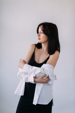 Portrait of a girl with black hair with a white sweater and a black dress.
