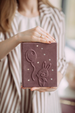 A girl in a business striped jacket presents a book with a handmade cover.