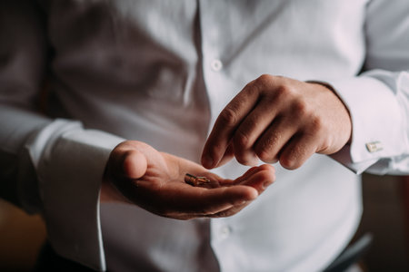 A large photo of mens hands buttoning cufflinks on shirt sleeves.