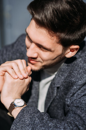 He is wearing a black wristwatch and appears to be indoors.の写真素材