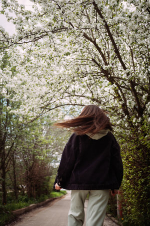 The person is wearing trousers and footwear, and the setting suggests a springtime outdoor walk.の写真素材