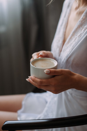 The image shows a person holding a cup of coffee.の写真素材