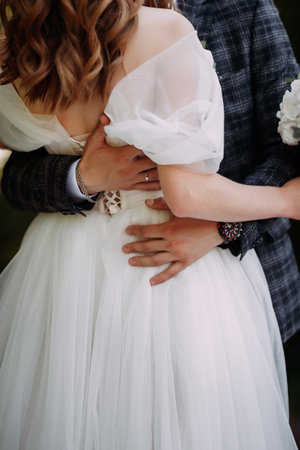 The woman is wearing a wedding dress and veil, and the couple appears to be sharing a kiss. The setting is outdoors.の写真素材