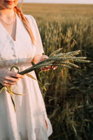 She is wearing a dress and is surrounded by grass and flowers.の写真素材