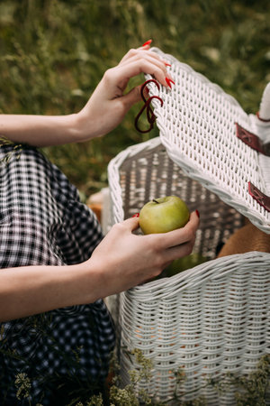 They are wearing clothing and holding a picnic basket containing an apple.の写真素材