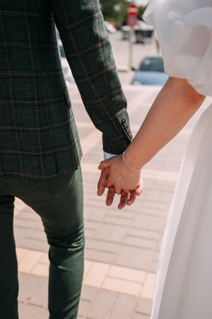 The woman is wearing a wedding dress, and the man is in trousers. The setting seems to be on a sidewalk or ground.の写真素材