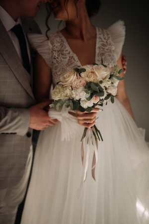 The woman is wearing a wedding dress and holding a bouquet of flowers. The man is dressed in a suit. The setting appears to be indoors, likely at a wedding ceremony or reception.の写真素材