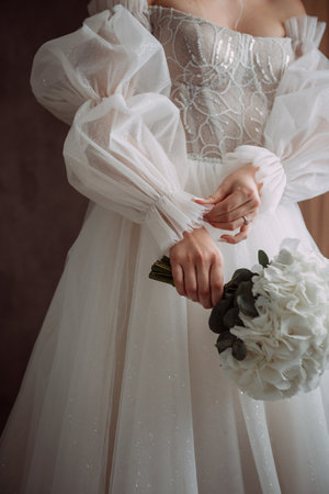 The individual appears to be dressed as a bride, possibly at a wedding ceremony. The attire includes a bridal veil and the bouquet is made up of roses. The setting is indoors.の写真素材