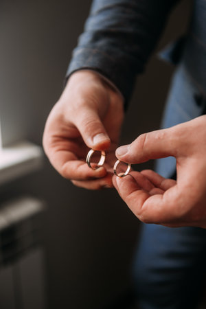 The image is of a pair of hands holding a wedding ring.の写真素材
