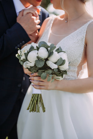 The bride is wearing a wedding dress and holding a bouquet, while the groom is in a suit. The setting appears to be outdoors.の写真素材