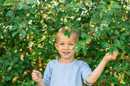 Happy smiling baby on the background of green cherry trees. copy spaceの写真素材