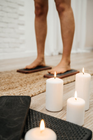 The legs of a girl standing on nails with lit white candles. sadhu board. Concept on healthy lifestyle.の写真素材