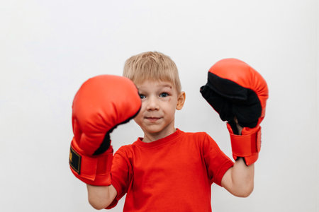 Boy in red boxing gloves on a white background with a scratch on his face. Protection. Self-defenseの写真素材