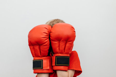 The boy covers his face with boxing gloves. Block, protection. The banner. Place for the textの写真素材